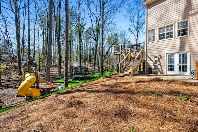 view of yard with stairs, a trampoline, a deck, french doors, and a playground