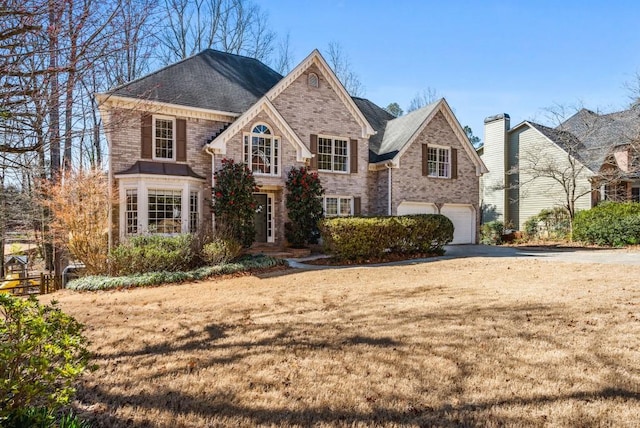 view of front facade featuring a front lawn, brick siding, driveway, and an attached garage