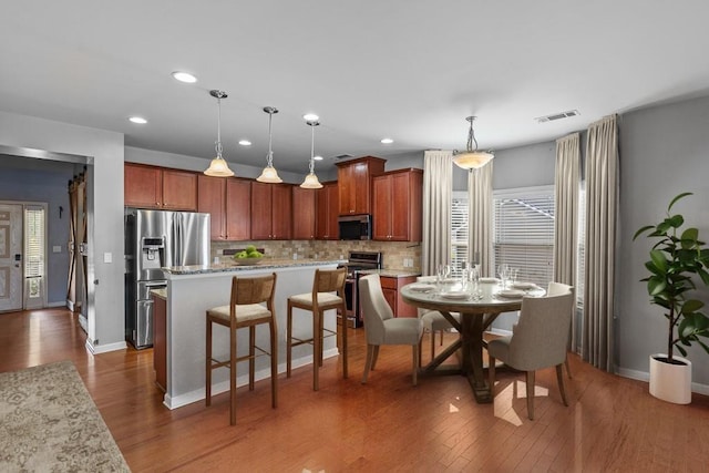 kitchen featuring dark hardwood / wood-style flooring, tasteful backsplash, stainless steel appliances, pendant lighting, and a kitchen island