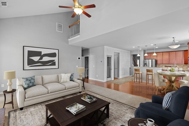 living room with ceiling fan, light wood-type flooring, and vaulted ceiling