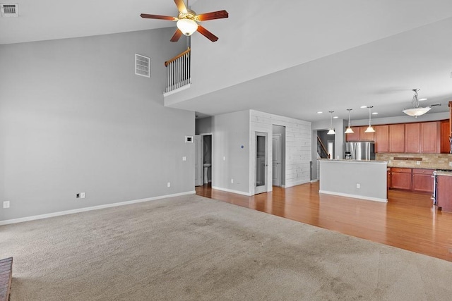 unfurnished living room featuring ceiling fan, light colored carpet, and lofted ceiling