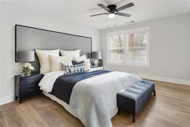 bedroom featuring a ceiling fan, visible vents, baseboards, and wood finished floors
