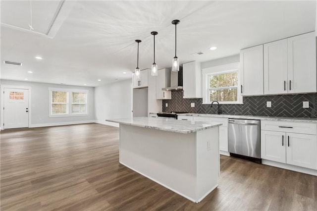 kitchen featuring decorative light fixtures, stainless steel dishwasher, white cabinetry, a kitchen island, and wall chimney exhaust hood