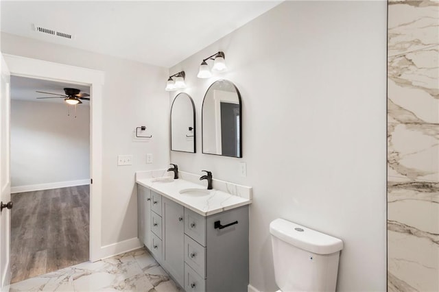 bathroom with marble finish floor, double vanity, visible vents, a sink, and baseboards