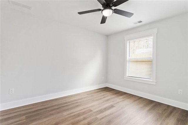 empty room featuring a ceiling fan, baseboards, visible vents, and wood finished floors