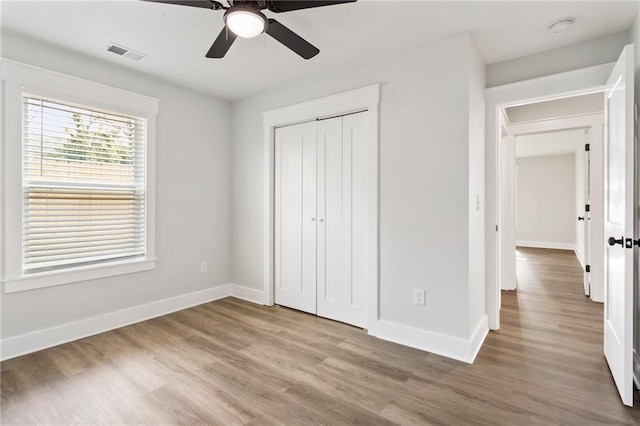 unfurnished bedroom featuring light wood finished floors, baseboards, visible vents, and a closet