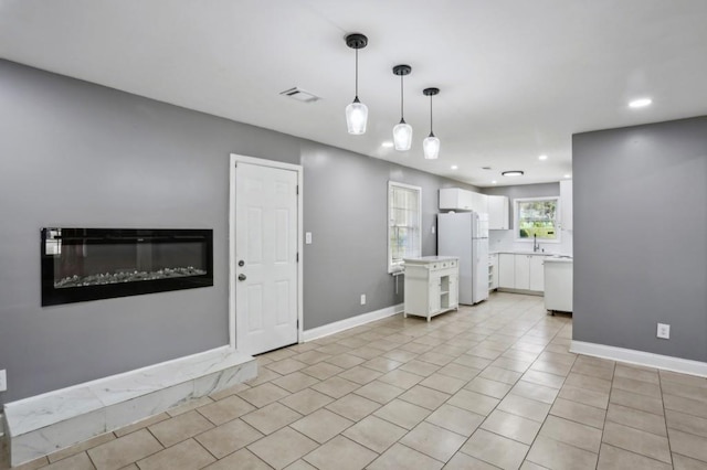 interior space with visible vents, baseboards, light countertops, freestanding refrigerator, and white cabinets