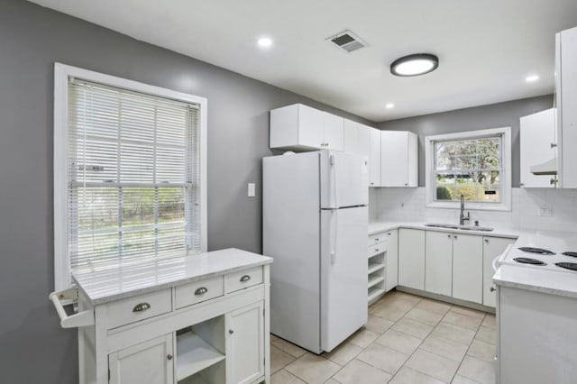 kitchen featuring tasteful backsplash, visible vents, freestanding refrigerator, and a sink