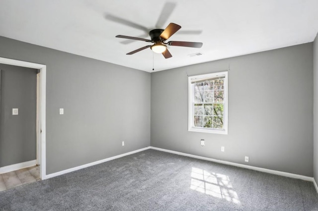 carpeted spare room featuring visible vents, ceiling fan, and baseboards