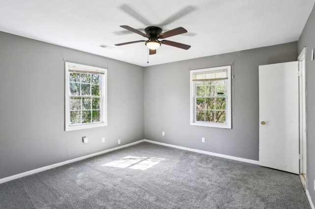 empty room with baseboards, visible vents, a wealth of natural light, and carpet floors