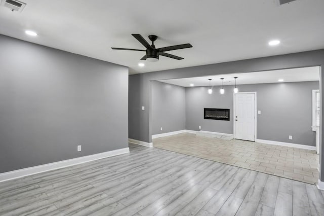 unfurnished living room featuring light wood-type flooring, visible vents, a ceiling fan, a glass covered fireplace, and recessed lighting