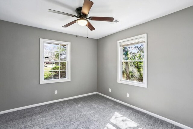 empty room with a healthy amount of sunlight, visible vents, carpet floors, and baseboards