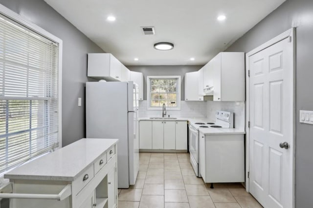 kitchen featuring backsplash, light tile patterned floors, white appliances, white cabinetry, and a sink