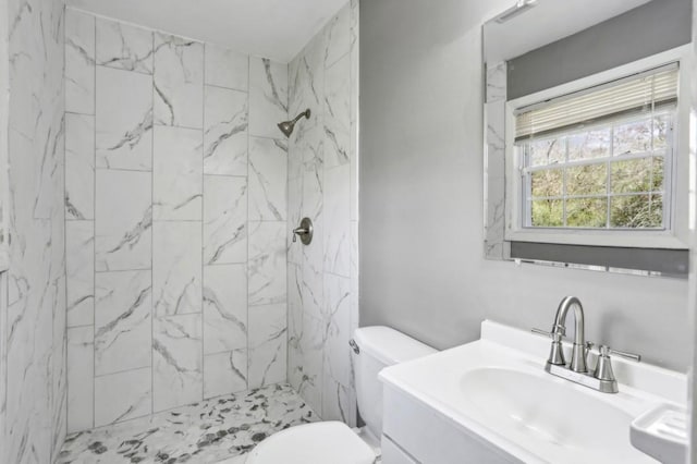 full bathroom with a marble finish shower, toilet, and vanity