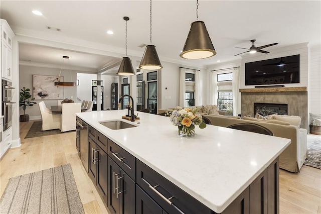 kitchen with a center island with sink, white cabinetry, sink, and pendant lighting