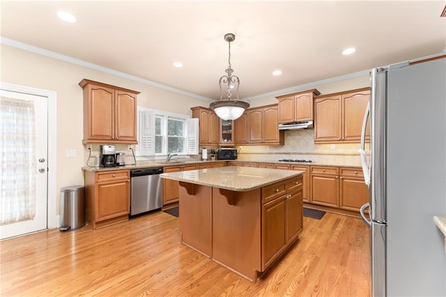 kitchen featuring hanging light fixtures, appliances with stainless steel finishes, a kitchen island, and light wood-type flooring