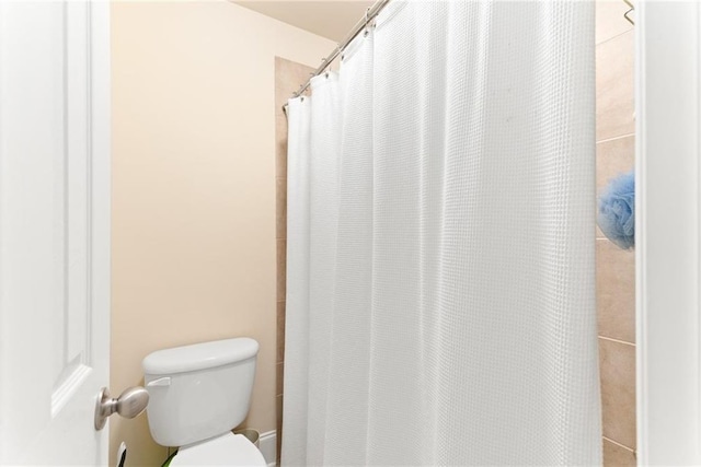 bathroom with toilet and a shower with shower curtain