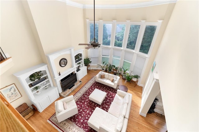 living room featuring crown molding, ceiling fan, and light hardwood / wood-style flooring