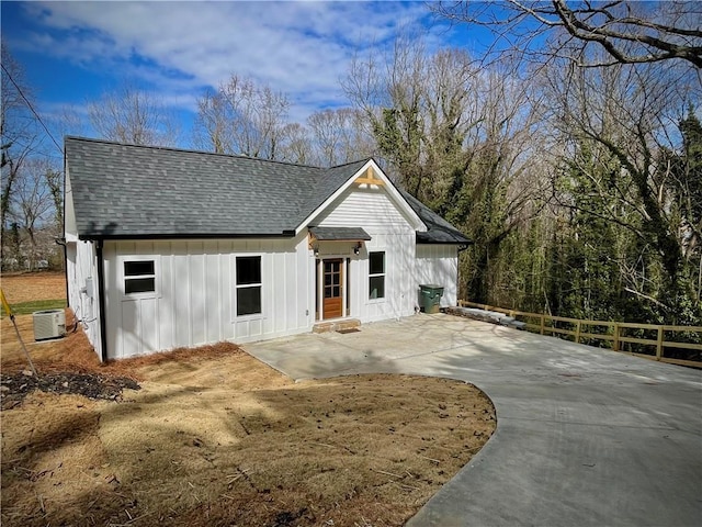 modern inspired farmhouse with a patio, a shingled roof, board and batten siding, and central air condition unit