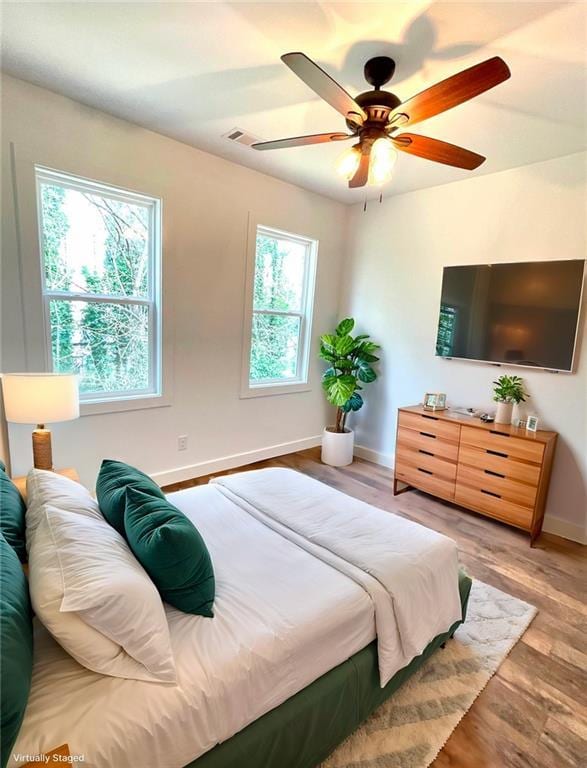 bedroom featuring visible vents, baseboards, ceiling fan, and wood finished floors