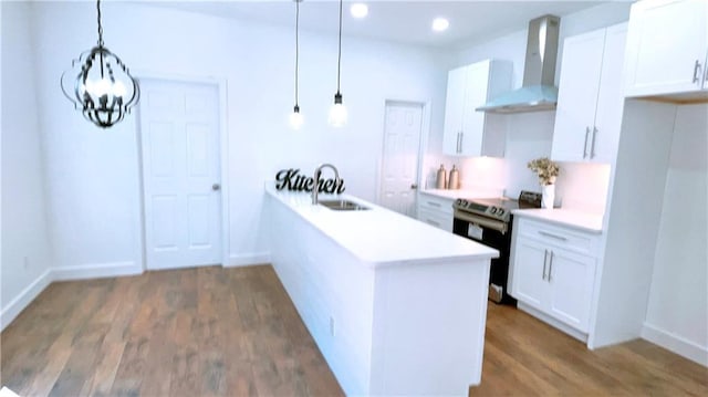 kitchen with pendant lighting, stainless steel electric range oven, light countertops, white cabinetry, and wall chimney exhaust hood