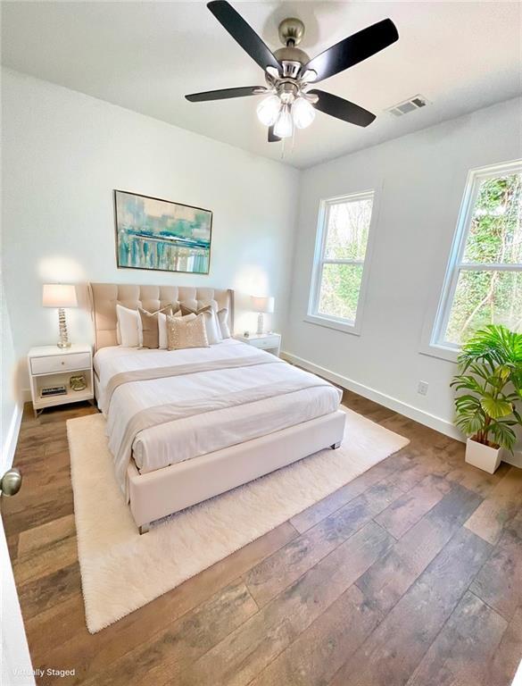 bedroom featuring visible vents, dark wood finished floors, baseboards, and multiple windows