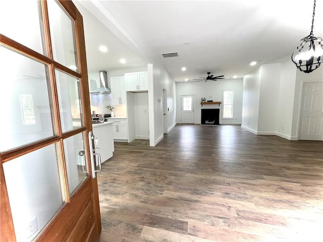 unfurnished living room with dark wood-type flooring, recessed lighting, visible vents, and ceiling fan with notable chandelier