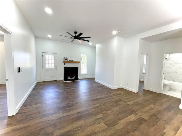 unfurnished living room featuring recessed lighting, dark wood-style flooring, a fireplace with raised hearth, and ceiling fan