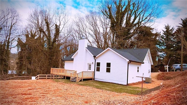 view of property exterior with a chimney, a wooden deck, and central air condition unit