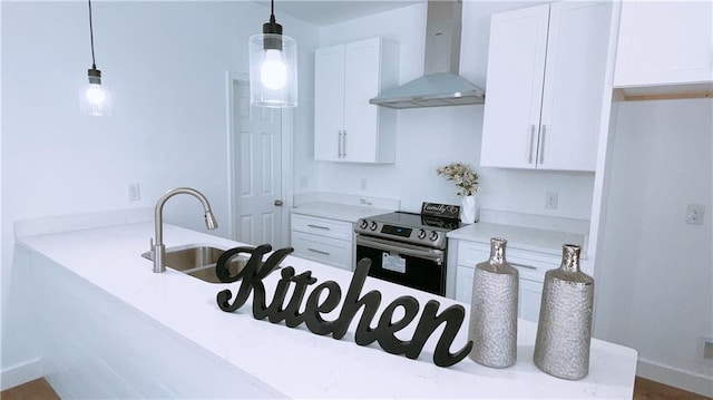 kitchen featuring pendant lighting, light countertops, stainless steel range with electric cooktop, white cabinets, and wall chimney range hood