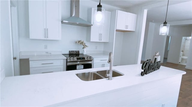 kitchen with pendant lighting, light countertops, electric range, white cabinetry, and wall chimney range hood