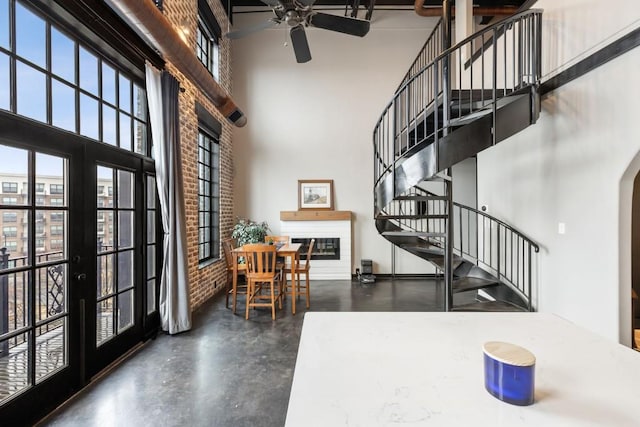 entryway featuring french doors, ceiling fan, brick wall, and a high ceiling