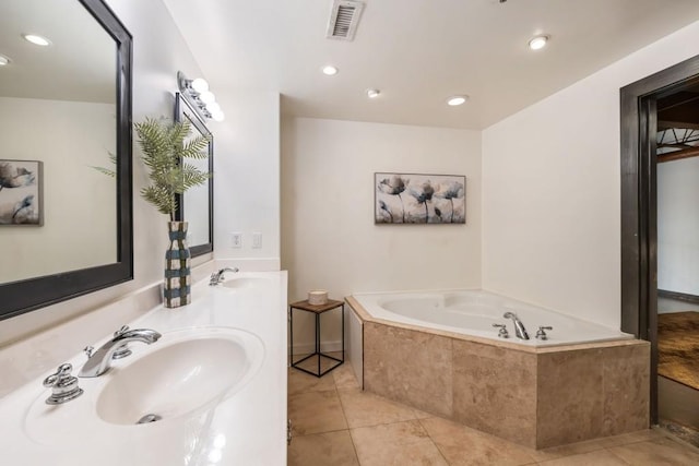 bathroom with tiled tub, vanity, and tile patterned flooring