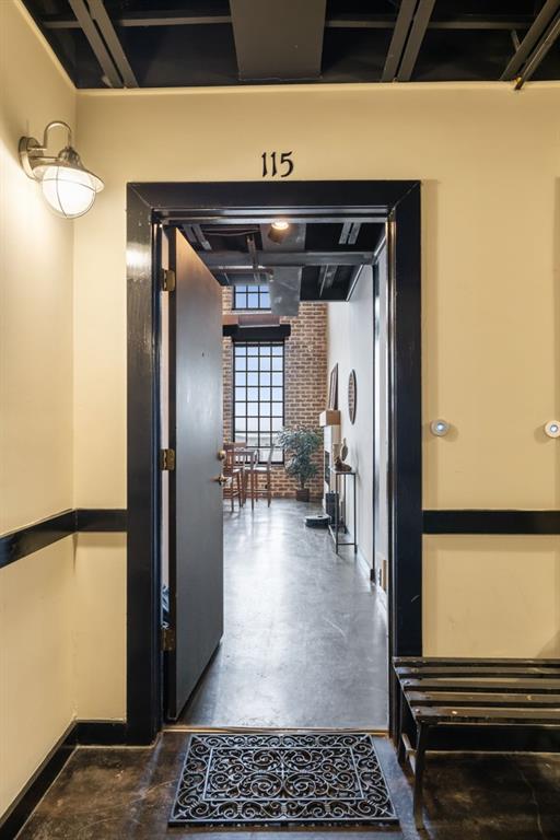 hallway featuring brick wall and concrete floors