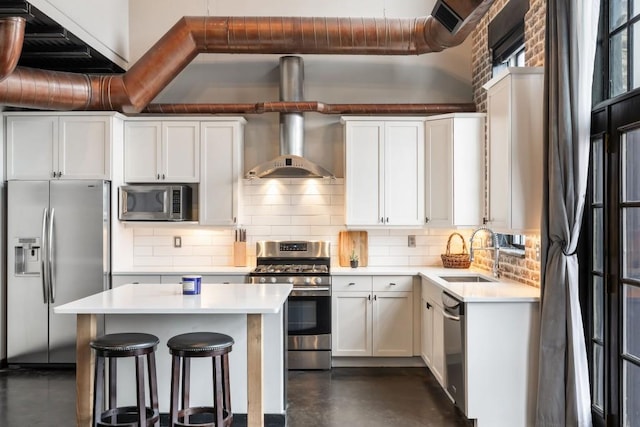 kitchen featuring white cabinetry, sink, backsplash, stainless steel appliances, and wall chimney exhaust hood