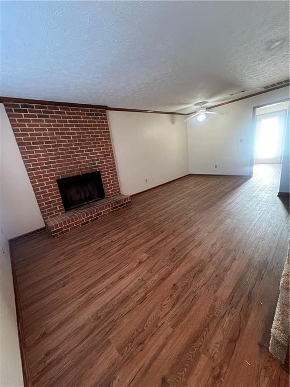 unfurnished living room with hardwood / wood-style floors, a textured ceiling, a brick fireplace, and ceiling fan