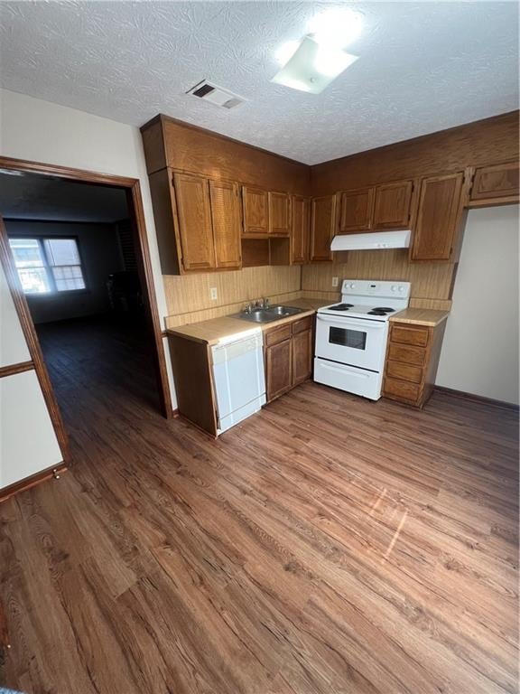 kitchen with a textured ceiling, light hardwood / wood-style floors, white appliances, and sink