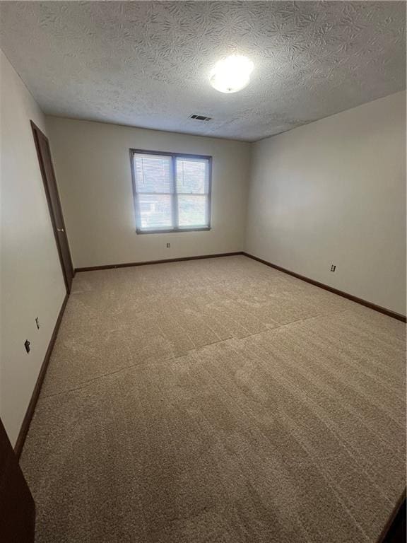 carpeted empty room featuring a textured ceiling