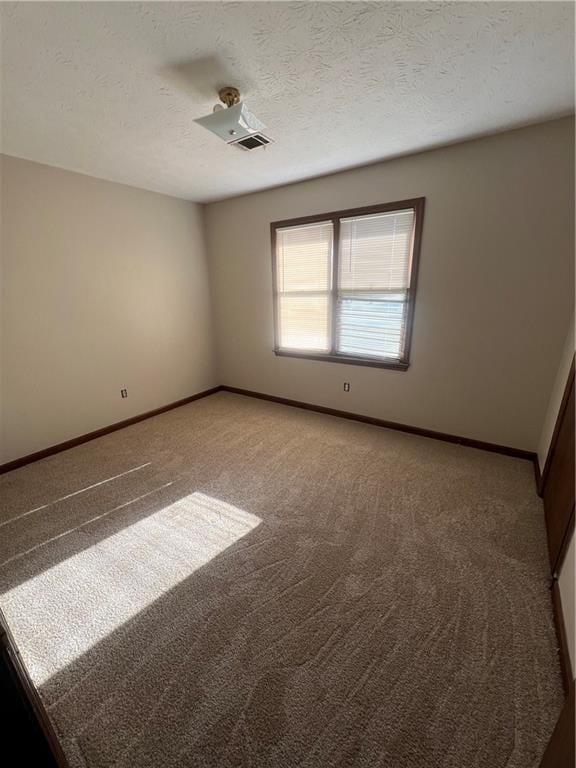 carpeted empty room with a textured ceiling