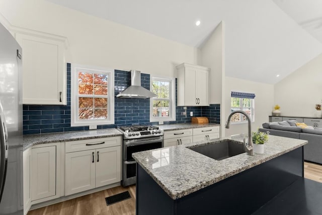 385 Jayne Ellen Way, Alpharetta, GA 30009 - kitchen featuring stainless steel appliances, wall chimney range hood, a sink, lofted ceiling, and light wood-type flooring