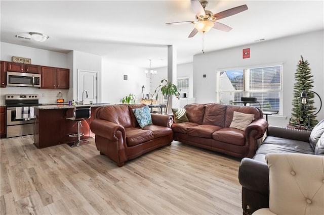 living room with light hardwood / wood-style flooring and ceiling fan with notable chandelier