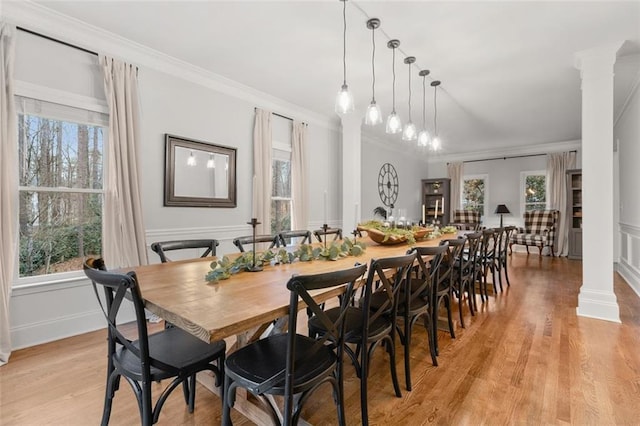 dining area with crown molding, light wood-style floors, baseboards, and ornate columns