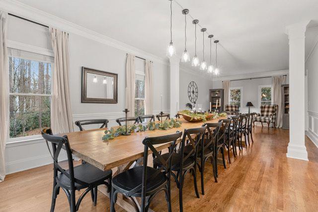 dining space featuring crown molding, light wood-style floors, and decorative columns