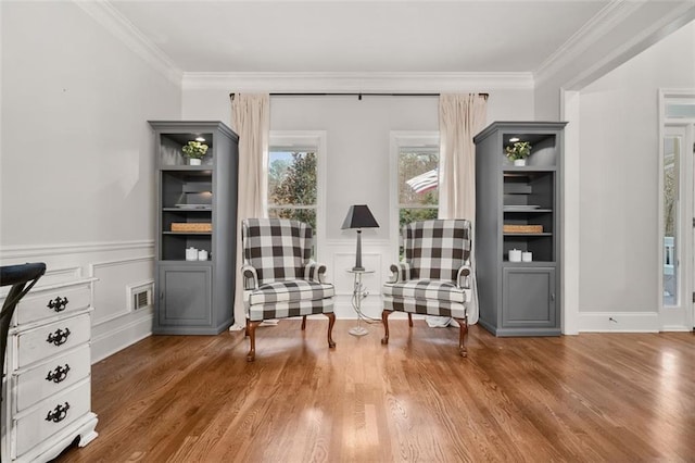 unfurnished room with ornamental molding, wainscoting, visible vents, and wood finished floors