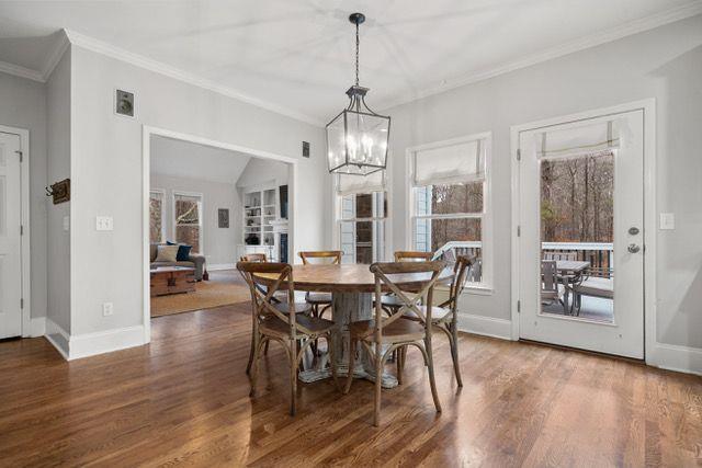 dining area with dark wood-type flooring, crown molding, and baseboards