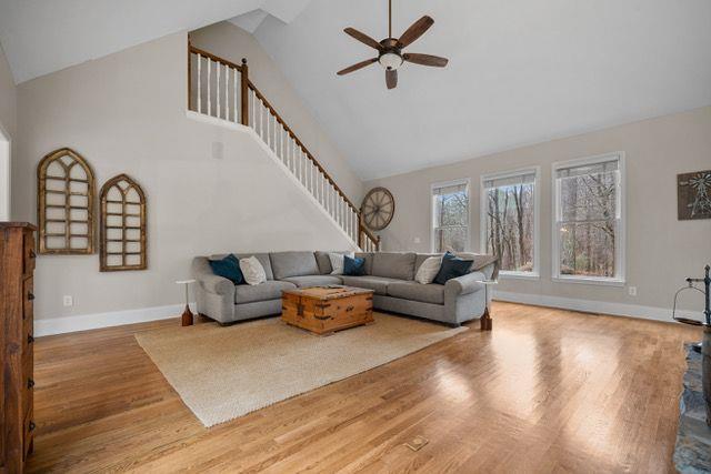 living room with light hardwood / wood-style floors, high vaulted ceiling, and ceiling fan