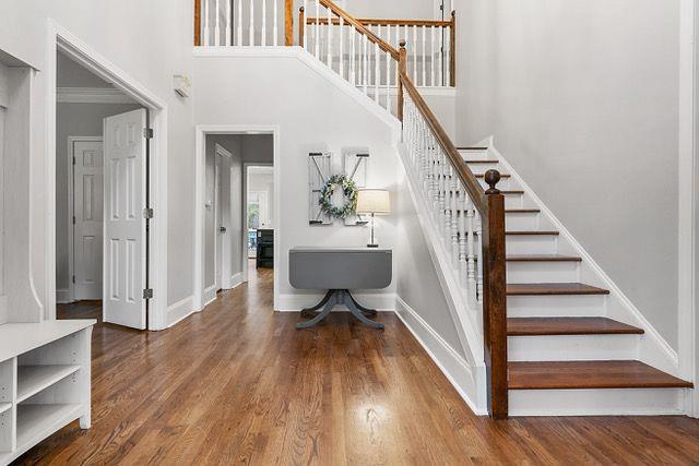 stairs featuring crown molding, a towering ceiling, and wood-type flooring