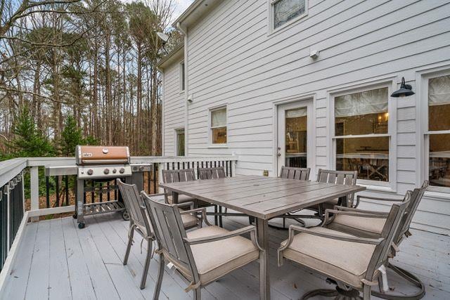 wooden deck with a grill and outdoor dining space