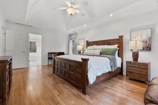 bedroom featuring ceiling fan, ornamental molding, connected bathroom, and light hardwood / wood-style flooring