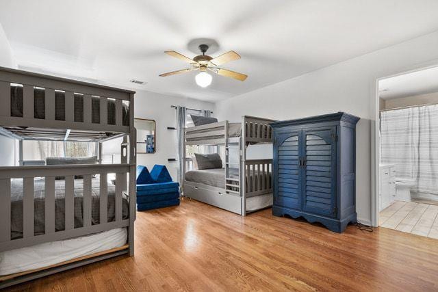 bedroom featuring connected bathroom, multiple windows, and wood finished floors